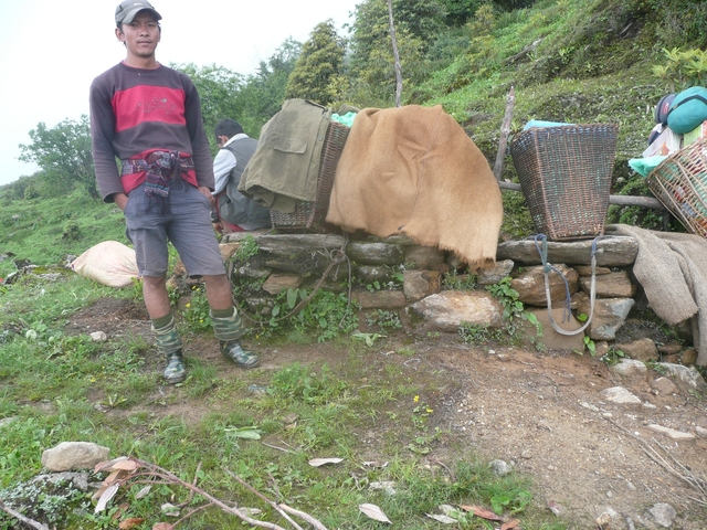 A partial view of people sitting with backpacks and equipment.