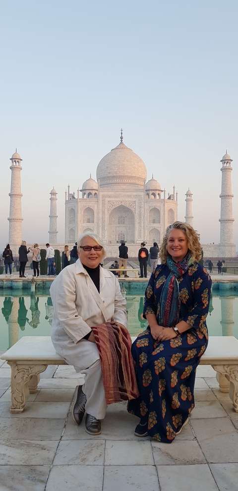 Two women smiling in front of the Taj Mahal.