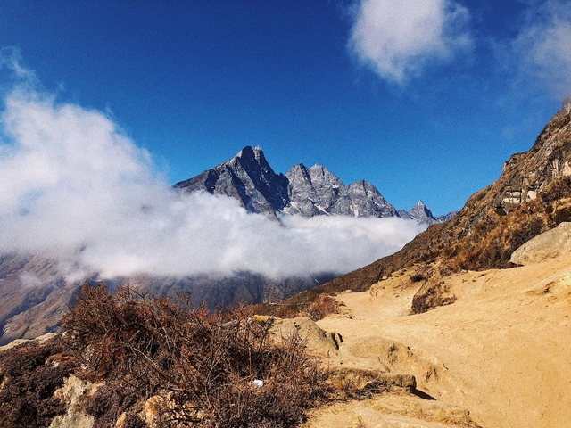 Majestic mountain peaks with clouds in a clear blue sky.