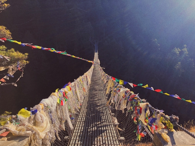 Suspension bridge adorned with colorful prayer flags.