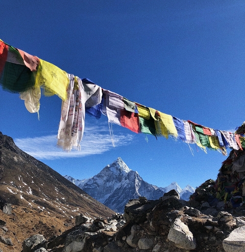 Colorful prayer flags fluttering with a mountain peak in the distance.
