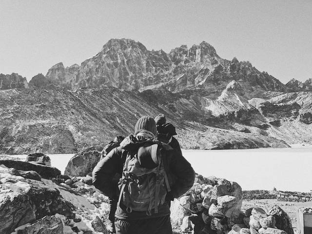 Back view of a person wearing a backpack, looking at a mountain range.