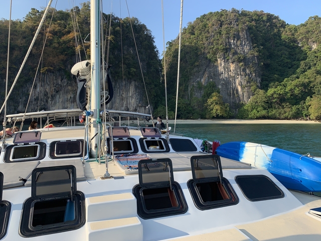 View from a catamaran showing sails and a limestone island.