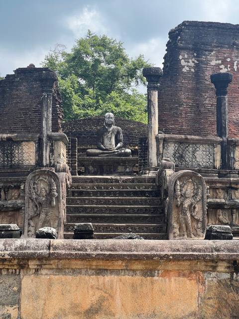 Ancient ruins with a Buddha statue in a meditation pose.