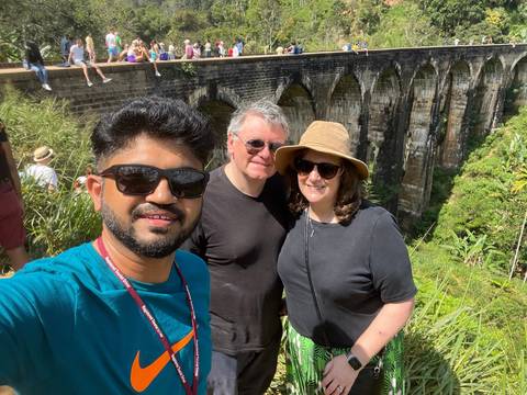 A group selfie on a railway bridge with a lush backdrop.