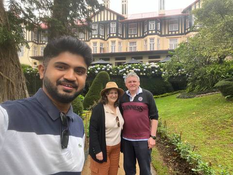 A group selfie in a garden setting in front of a large hotel.
