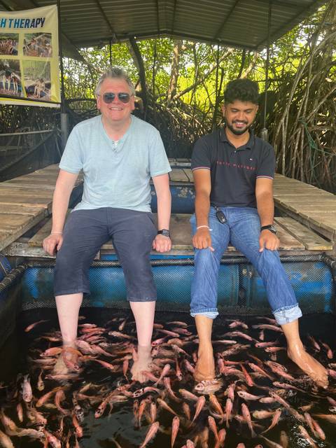 Two men sitting on a log raft, one smiling.