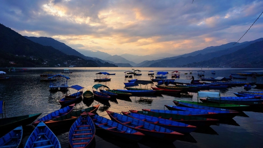 Vibrant boats floating on a lake at sunset.