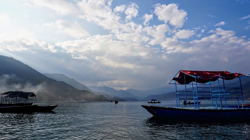 Boats on a calm lake with mountains in the background.