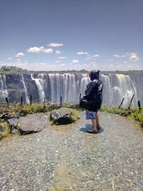 Person in a raincoat facing the majestic Victoria Falls.