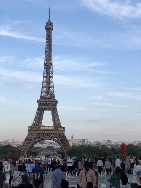 The Eiffel Tower with a crowd of people around it.