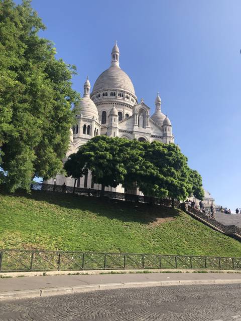 A large white basilica with a green lawn, seen from a side angle.