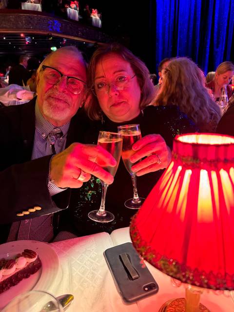 Two people raising glasses to celebrate at a restaurant.