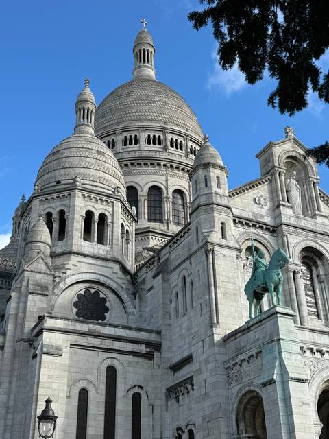 A detailed close-up of the Sacré-Cœur Basilica against a blue sky.
