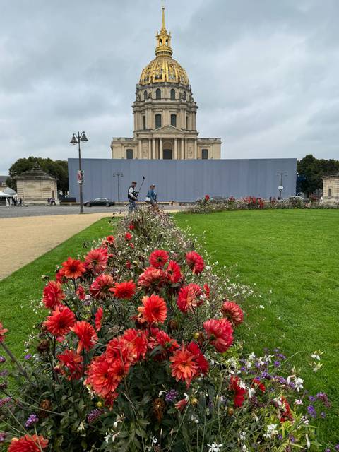 A domed building with red flowers in the foreground.
