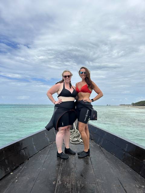 Two women in snorkeling gear posing on a boat.