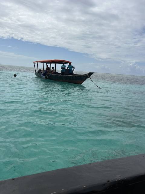 Small boat on clear turquoise water.