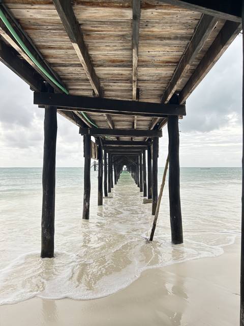 Wooden pier structure over sandy beach and ocean.
