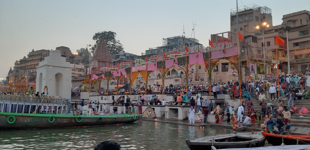 A vibrant riverside with colorful decorations and crowds of people.