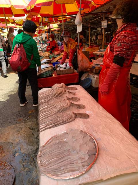 Busy market scene with seafood display and patrons.