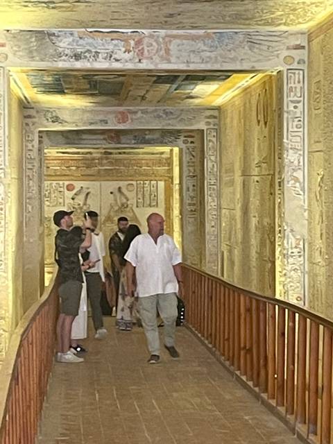 People walking through a corridor with ancient wall art.
