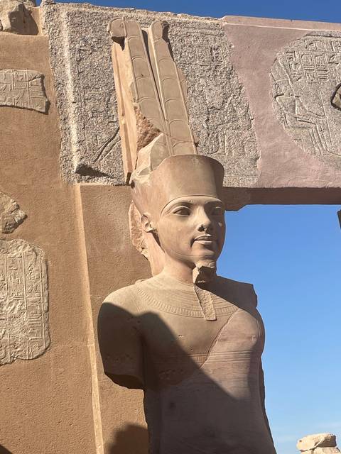 Statue of a pharaoh on a stone pedestal.