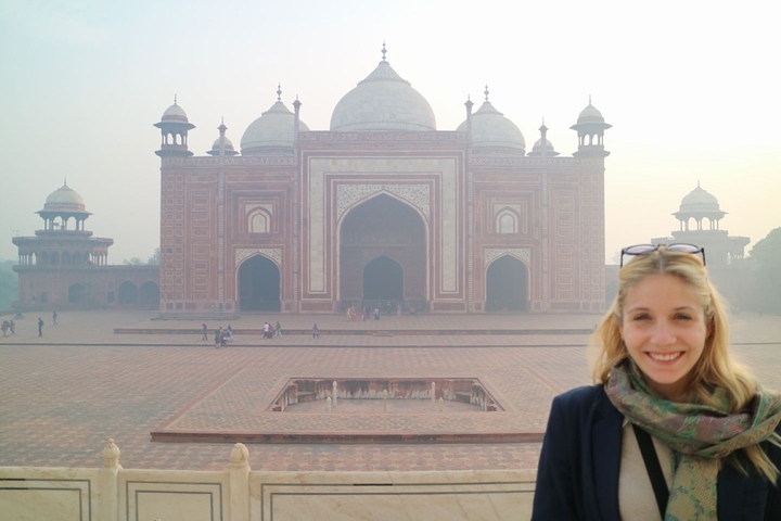 Person smiling in front of a Taj Mahal-style building