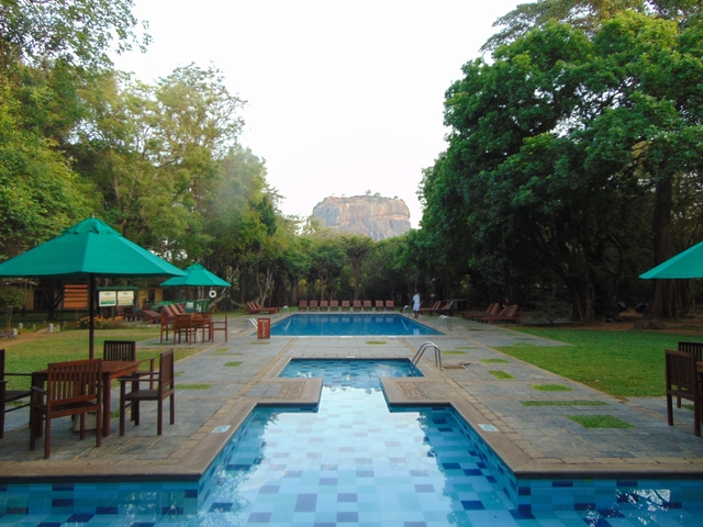 A pool area with Sigiriya Rock in the distance.
