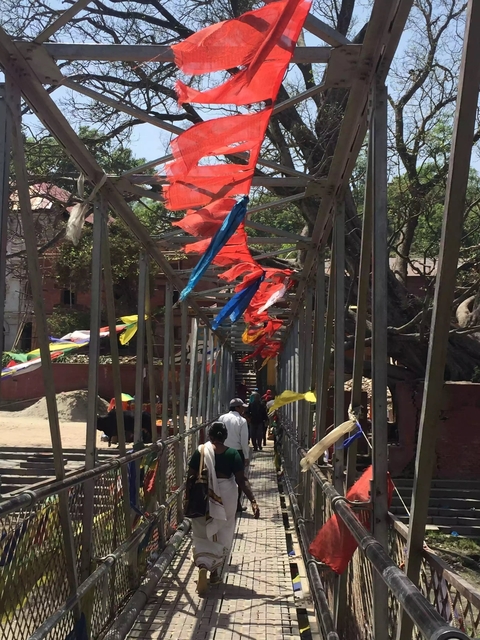 Bridge decorated with colorful prayer flags with people walking.