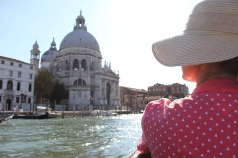 Person with a hat looking at Santa Maria della Salute over the water.