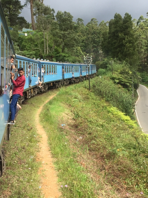 Train journey with people hanging out of windows.