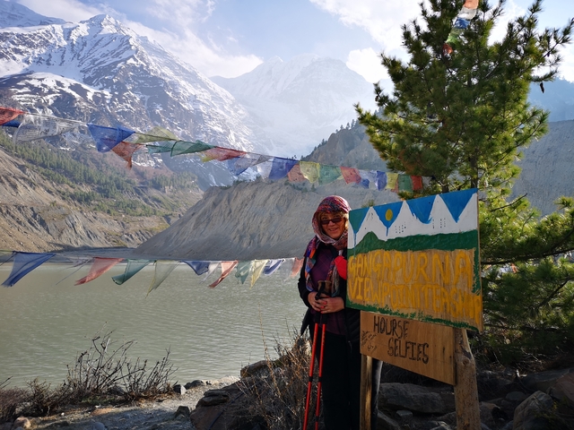 Woman with colorful headscarf beside lake with mountains in background