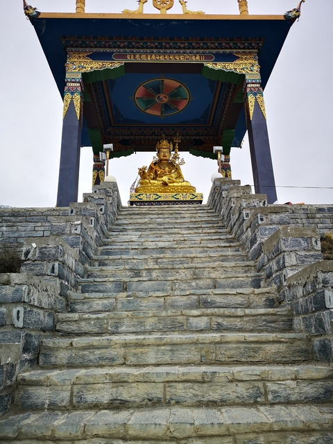 Gold statue atop stone steps with colorful decorations