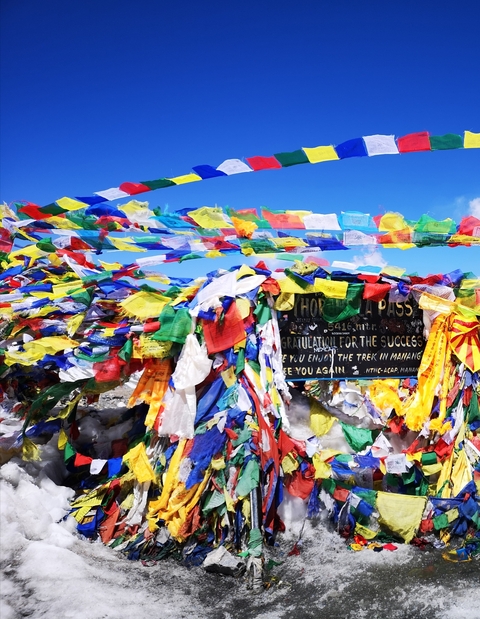 Colorful prayer flags on a mountain pass sign