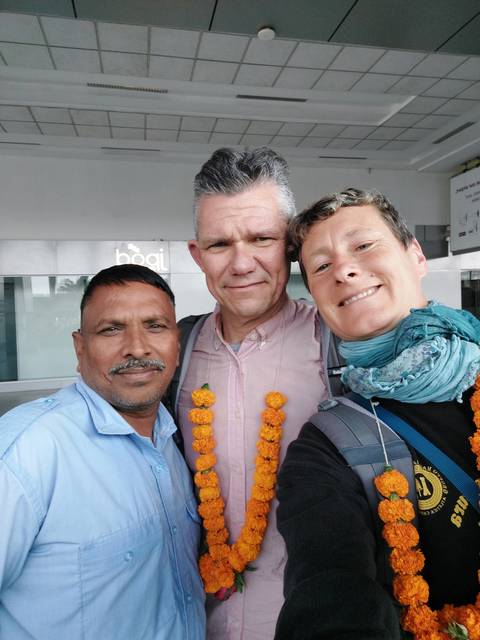 Three people taking a selfie, adorned with garlands.