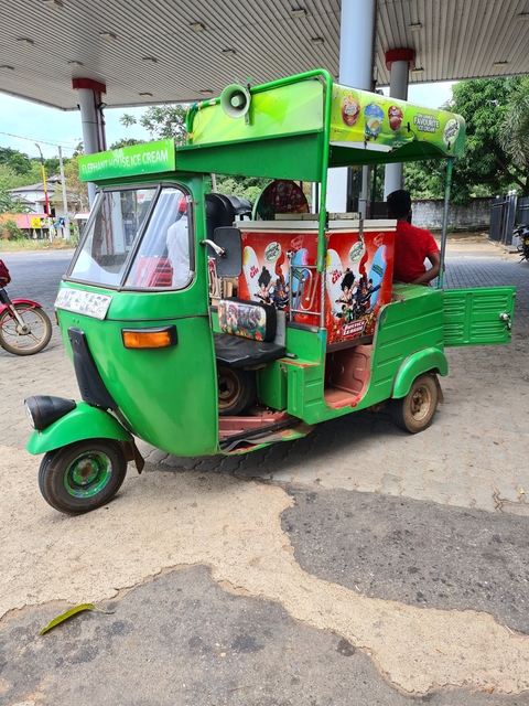 Green tuk-tuk parked on street.