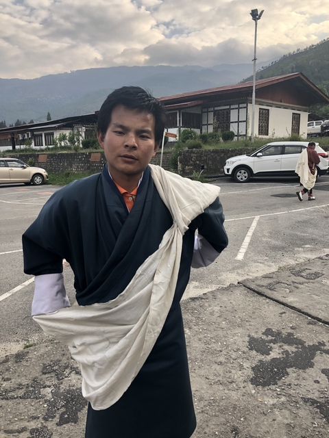 Person in traditional clothing standing in a parking lot.
