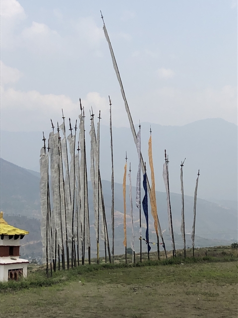Tall prayer flags against a mountain backdrop.