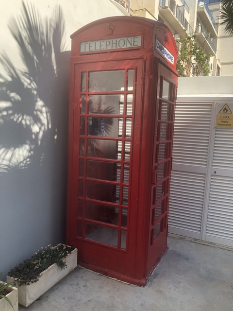 Red telephone booth next to a modern building.