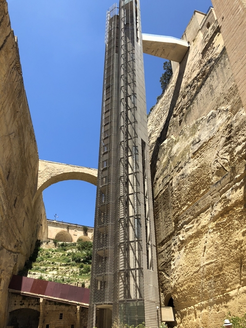 Modern elevator structure between ancient stone walls.
