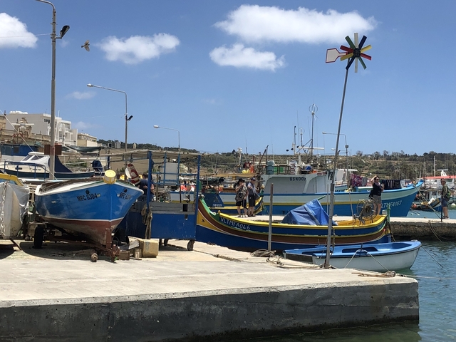 Colorful fishing boats in a small harbor under a blue sky.
