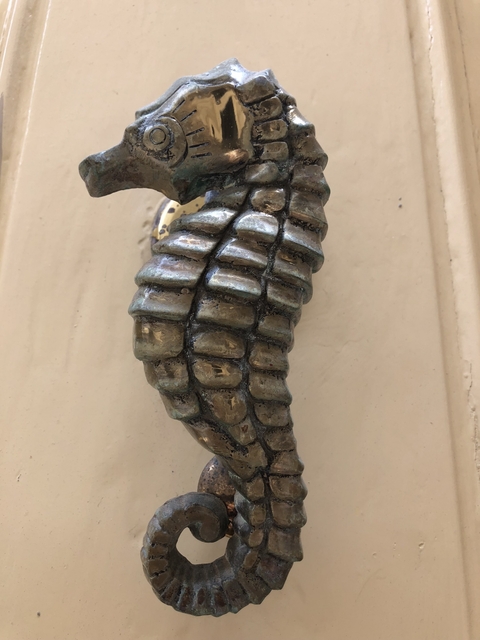 Close-up of an ornate, metallic door knocker shaped like a hand.