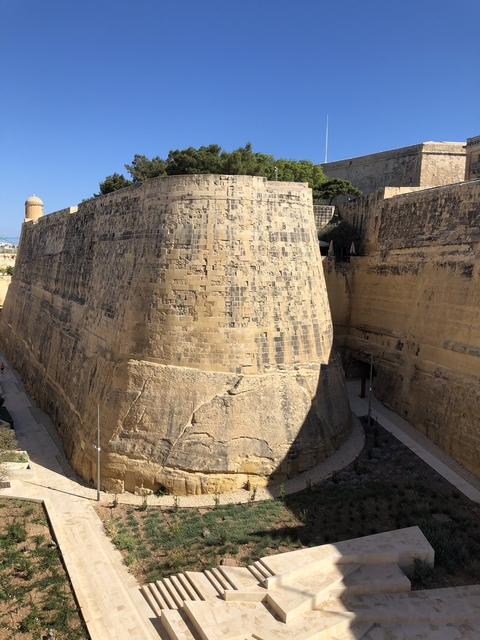 Massive stone fortification wall under a clear blue sky.