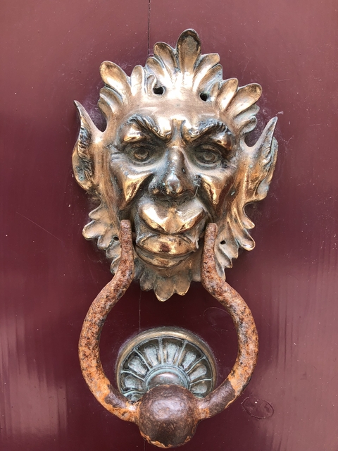 Rustic metal face sculpture attached to a door.