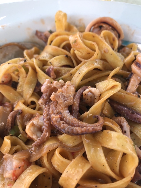 Close-up of seafood pasta with visible octopus tentacles.