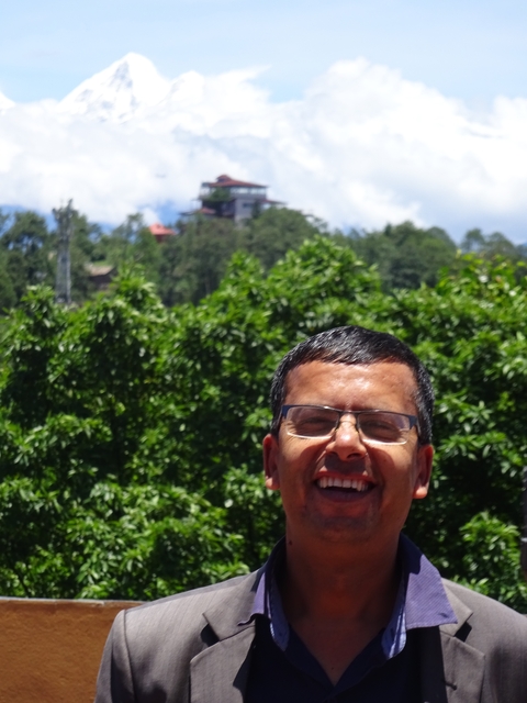 Man smiling with trees in the background.