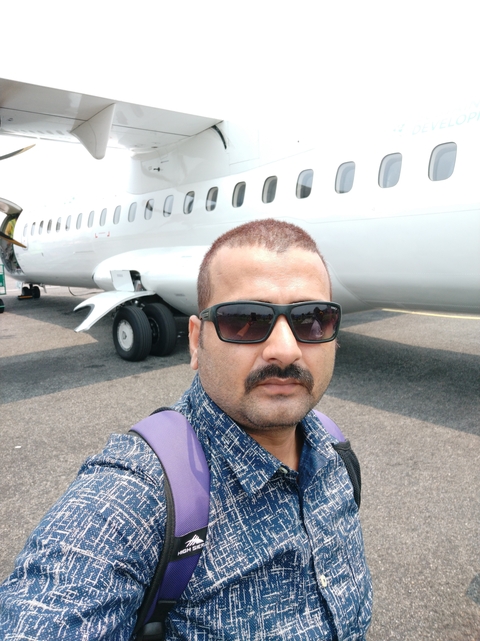 Traveler takes a selfie on the tarmac beside a small passenger aircraft.