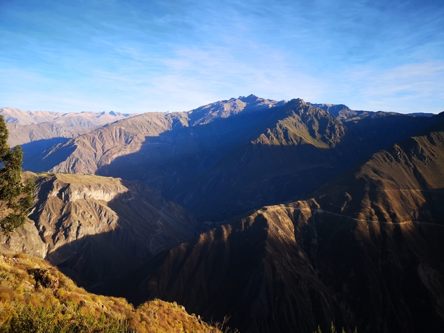 Mountain and valley view under a bright blue sky and sunlight.