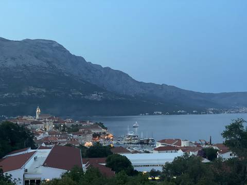 Upside-down coastal town with boats and mountains backdrop.