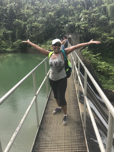 Smiling woman on a bridge over water.
